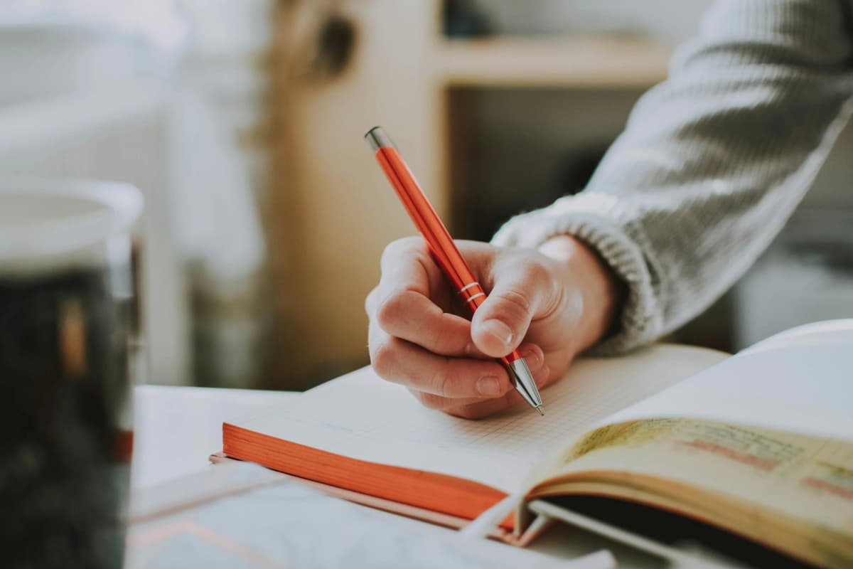 Person with notebook and pen, working on journaling with focus and intention