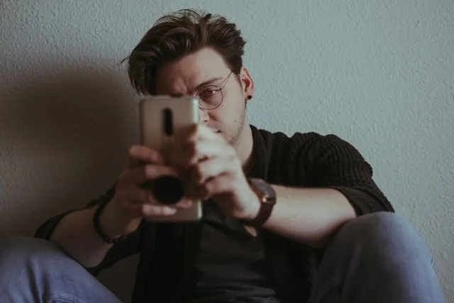 Person looking at phone with frustrated, overwhelmed expression